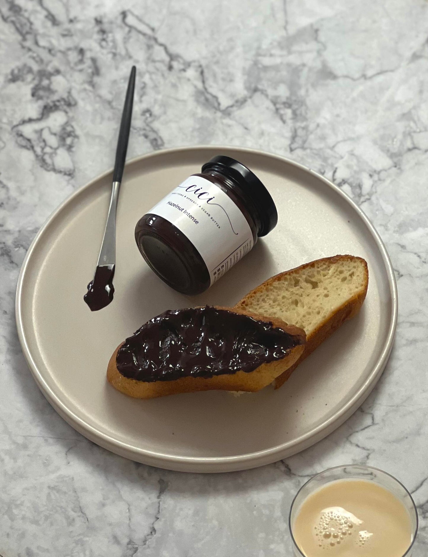 Dark chocolate hazelnut spread on a slice of baguette with marble background